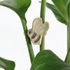 small ceramic and glass bumble bee plant hugger, with wire legs attached to the stem of a house plant