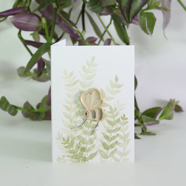 small ceramic and glass bumble bee on gift card with watercolour leaves