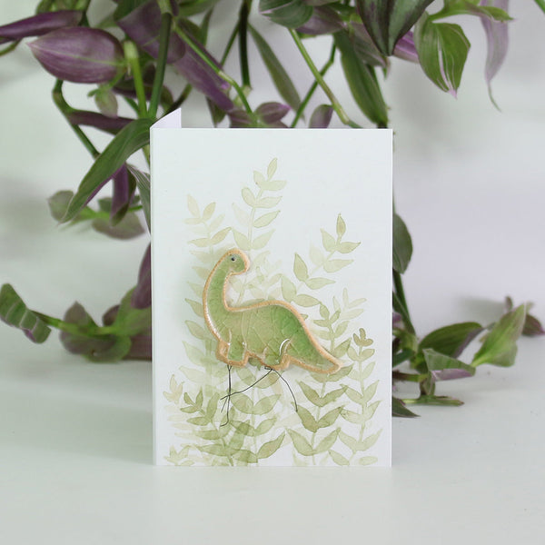 small ceramic and glass green brontosaurus dinsoaur plant decoration on gift card with watercolour leaves