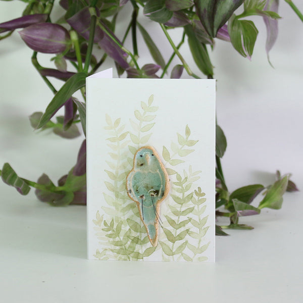 small ceramic and glass budgie plant decoration, on giftcard with watercolour leaves