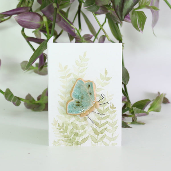 small ceramic and glass plant decoration on gift card with watercolour leaves