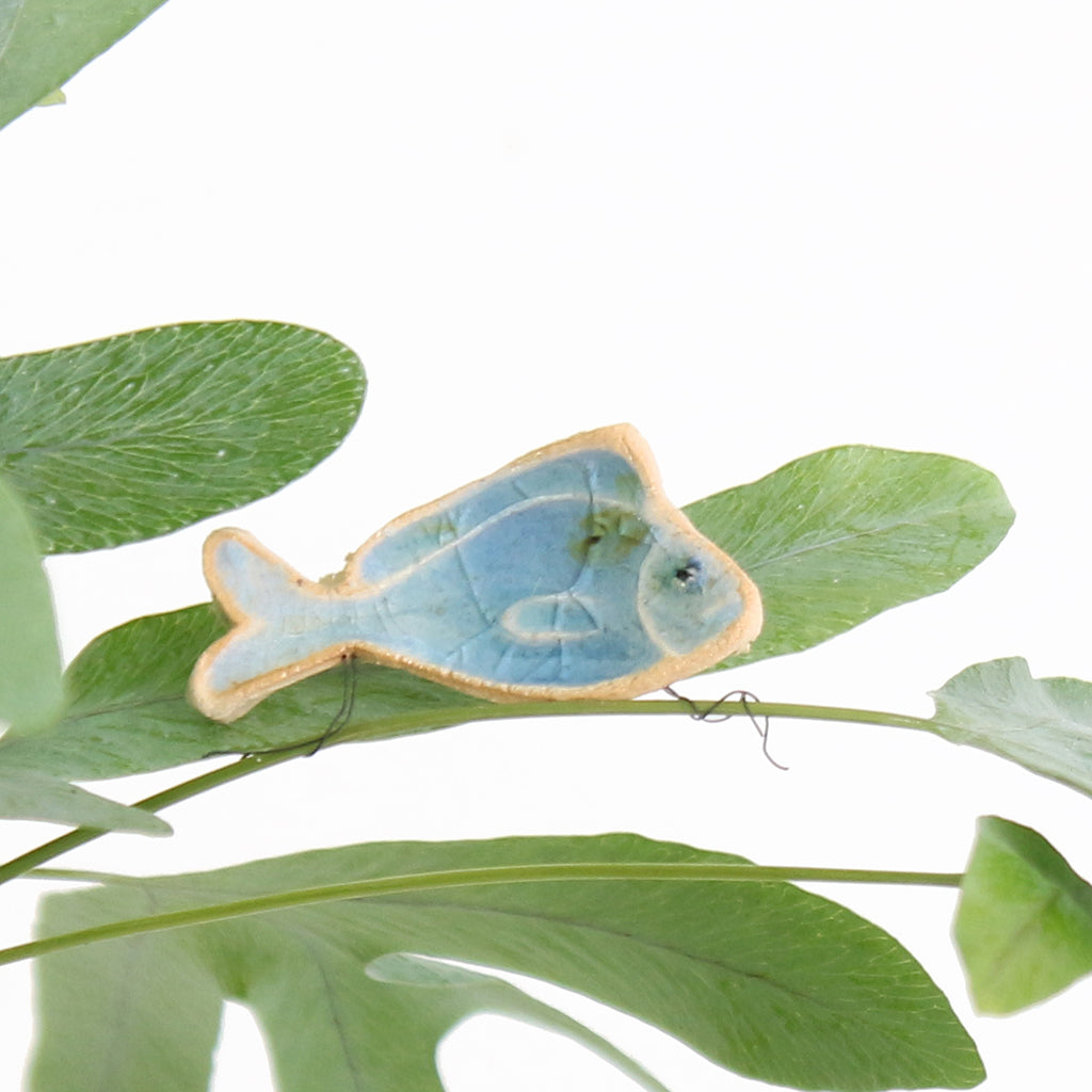 small ceramic and glass sapphire blue fish plant decoration, with thin wire wrapped around house plant stem