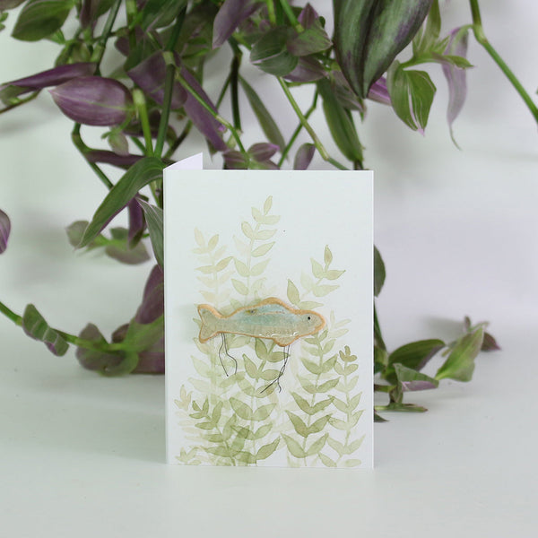 small ceramic and glass aqua blue fish plant decoration on gift card with watercolour leaves