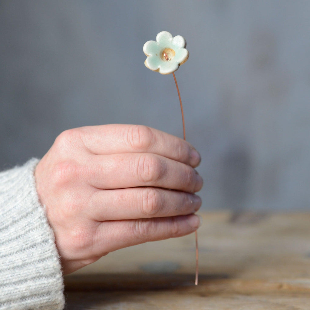 Hand holding green ceramic flower bud stem